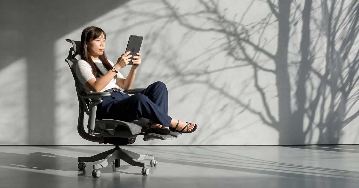 Person testing a cross-legged sitting position in a wide-seat ergonomic chair