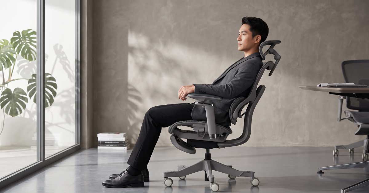 Person testing the fit and movement of a Niture ergonomic chair